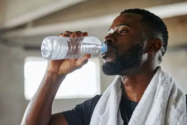 Image of man drinking water to improve hydration Banbury after work out.